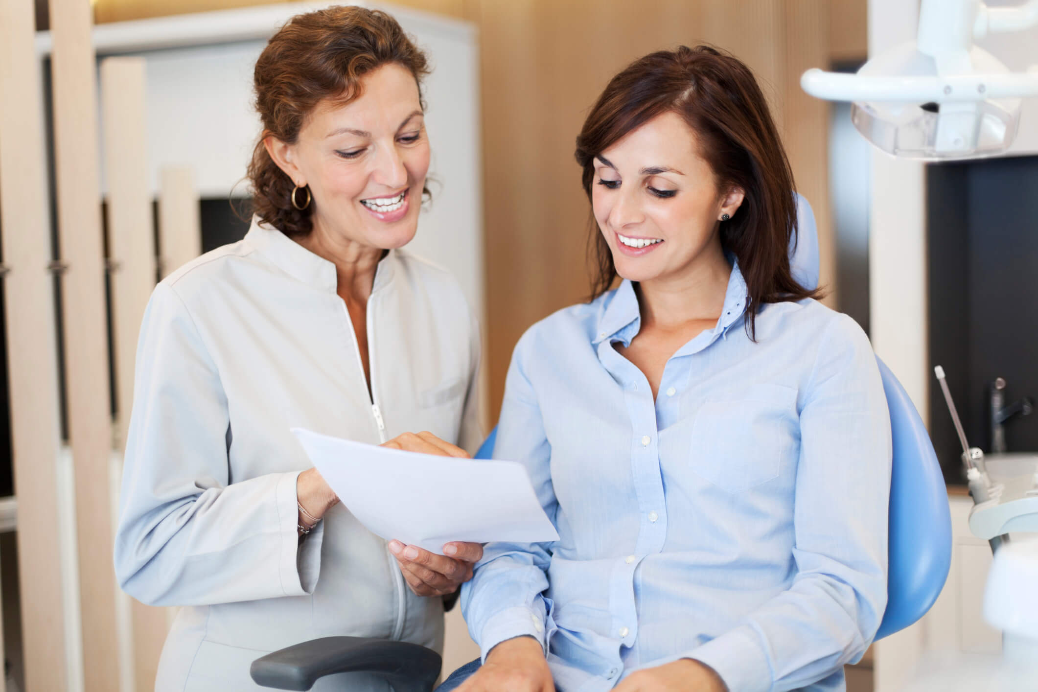 Dentist explaining a woman's invoice after a dental cleaning in the office